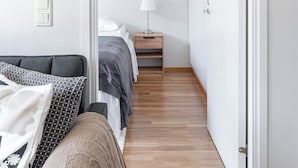 A narrow hallway leading to a bedroom with a bed, bedside table, and a lamp. - Comfy 1BR Apt with Sauna - Best Location (Jyväskylä)