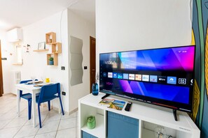 Ein modernes Wohnzimmer mit einem Flachbildfernseher, einem Esstisch mit Stühlen und eingebauten Regalen.