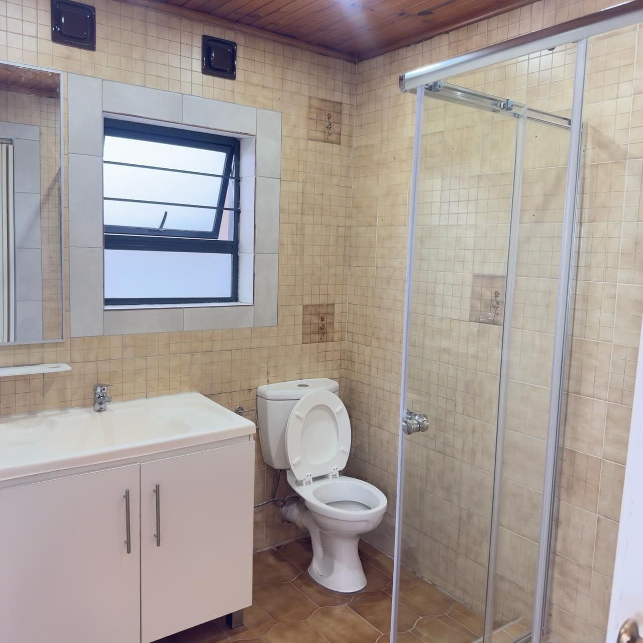 Un baño con inodoro, lavabo, espejo y cabina de ducha.
