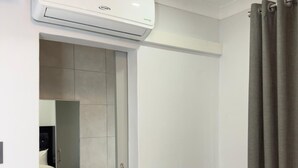 A bathroom with a modern sink, mirror, and a white air conditioning unit. - Cozy Villa Lodge (Edenvale)