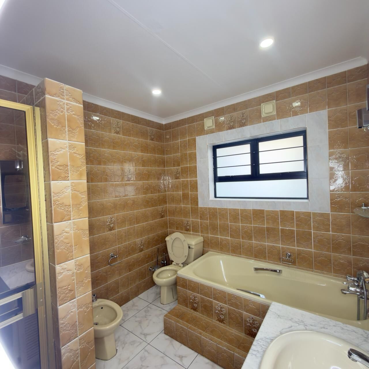 Une salle de bain avec une baignoire, des toilettes, un bidet et une fenêtre.