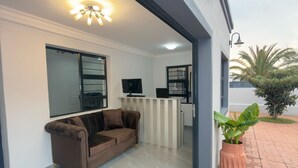 A modern outdoor living area with a sofa, a TV, and a potted plant. - Cozy Villa Lodge (Edenvale)