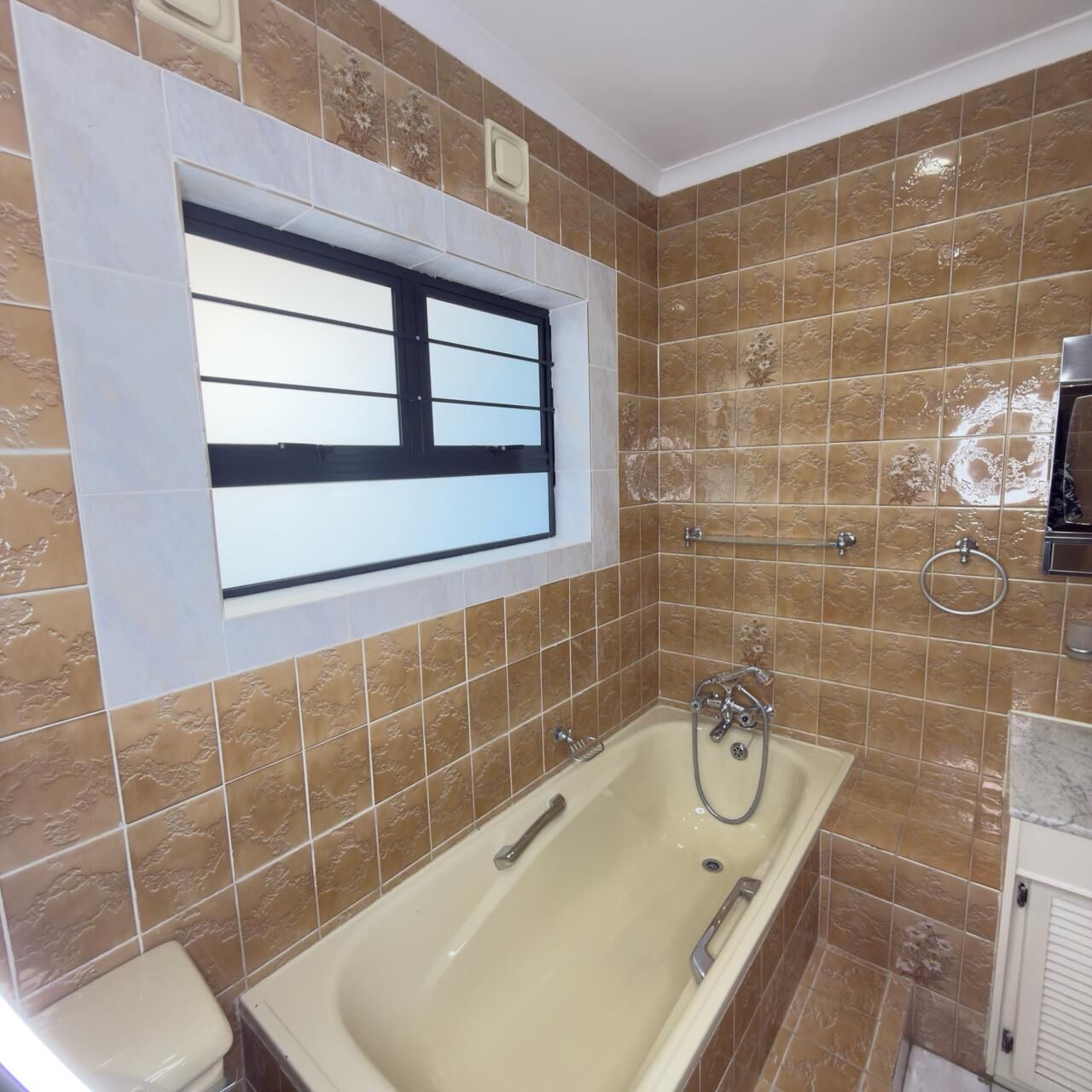 A bathroom with a bathtub, a window, and a towel ring.