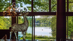 A view of a lake from a room with large windows, a decorative deer figurine, and a windmill in the distance. - An Artist's Story: A Private Sanctuary-devoted to art and quiet poetry..... (Logan)