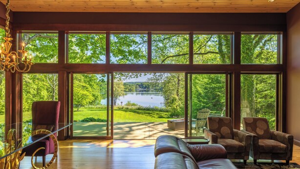 A spacious room with large windows, a leather sofa, two armchairs, and a chandelier. - An Artist's Story: A Private Sanctuary-devoted to art and quiet poetry..... (Logan)