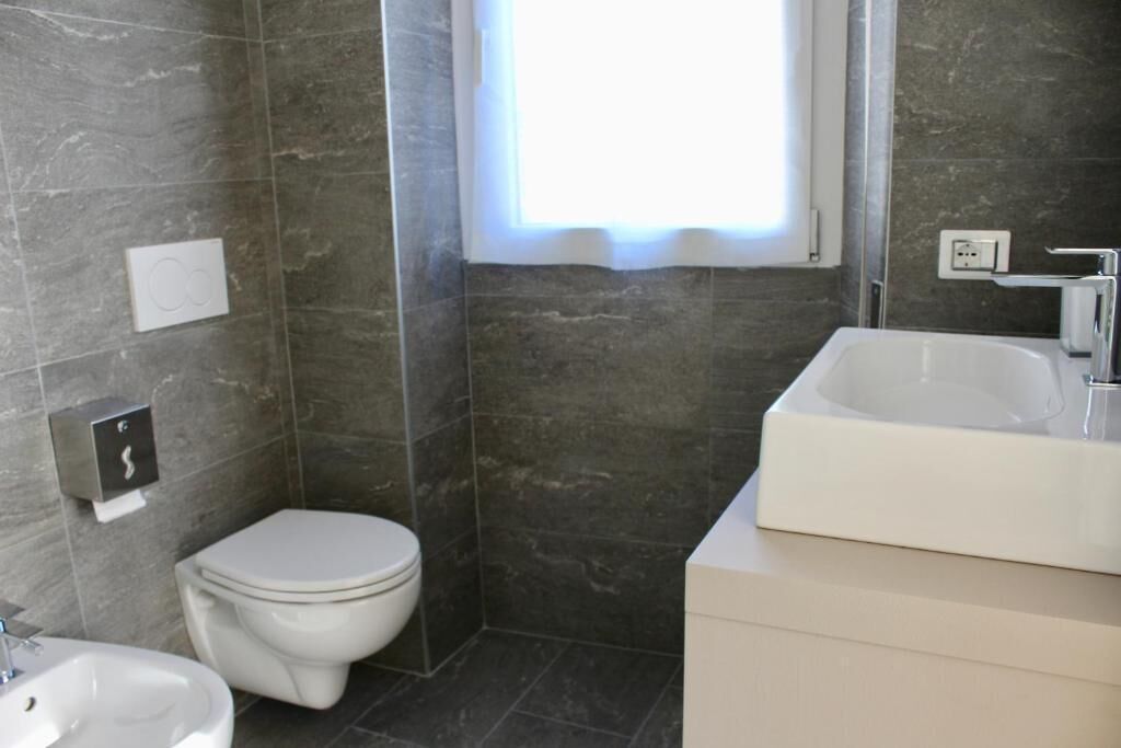 A modern bathroom with a toilet, bidet, and a large sink.
