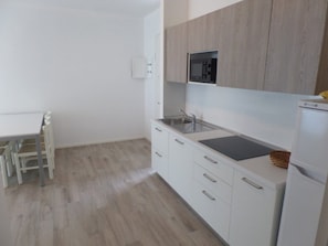 A modern kitchen with white cabinetry, a built-in microwave, and a sink. - Stylish holiday flat with rooftop pool (Bibione)