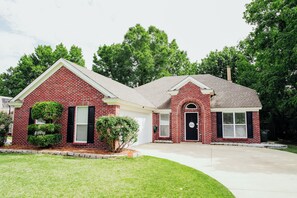 A two-story brick house with a garage, a front porch, and a small front yard. - Copperfield Retreat 3BR | Pet-Friendly Escape (Montgomery)