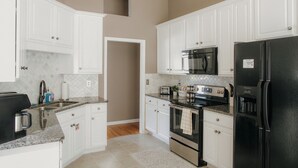A kitchen with white cabinets, a black refrigerator, a microwave, and a stove.