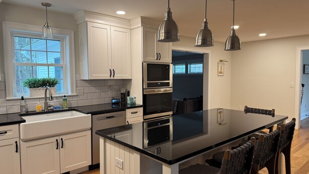 A modern kitchen with white cabinetry, a large island, and pendant lighting.
