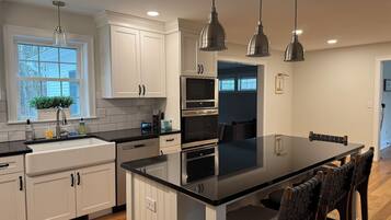 A modern kitchen with white cabinetry, a large island, and pendant lighting.
