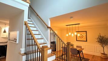 A staircase with wooden steps and black railings, leading to a dining area with a table and chairs.