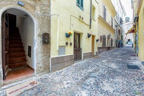 A narrow cobblestone street with a staircase leading to a building entrance. - Studio 'Domus Santa Barbara' with Wi-Fi (Alghero)