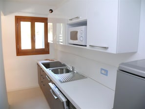 Eine kleine Küche mit Mikrowelle, Spüle und Kühlschrank.