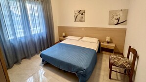 Una habitación de hotel con una cama, dos mesitas de noche, una silla y obras de arte en las paredes.