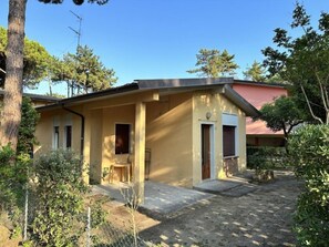 A two-story building with a covered porch, a small table, and a chair. - Functional stay for five guests in Bibione (Bibione)