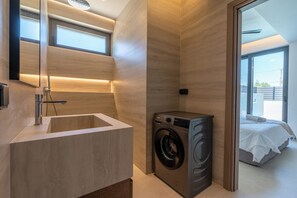 Ein modernes Badezimmer mit integriertem Waschbecken, einer Waschmaschine und einem großen Spiegel.