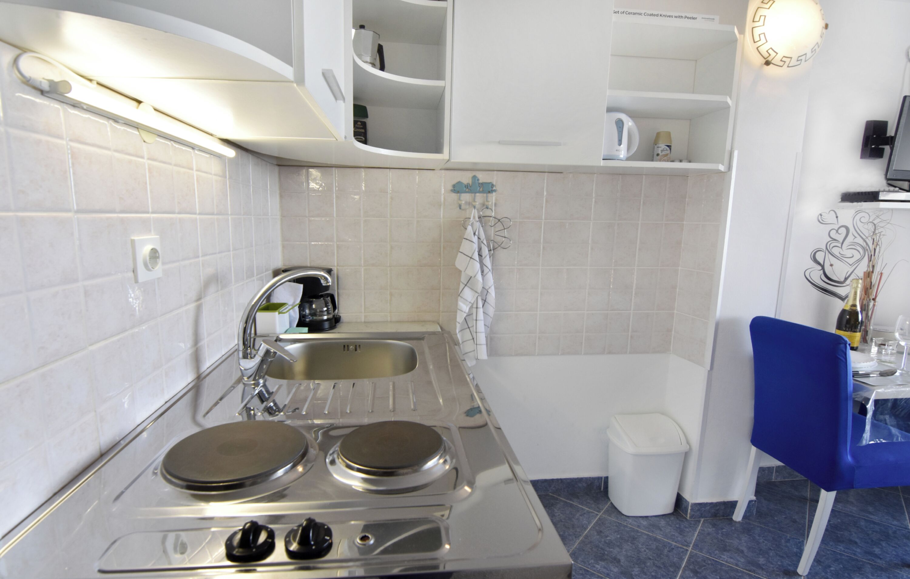 A kitchen with a stove, sink, and white tiled walls.