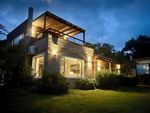 A modern two-story house with a stone facade, large windows, and a covered patio area. - Magnificent Views and Comfort in Punta Colorada (Punta Colorada)