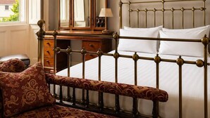A bedroom with a bed, a bench, a dresser, and a mirror.