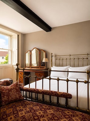 Une chambre Ă coucher comprenant un lit, un banc, une commode et un miroir.