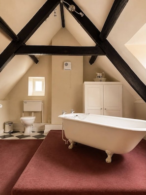 A bathroom with a freestanding bathtub, a toilet, a window, and a cabinet. - The Old Manor House Hotel (Keynsham)
