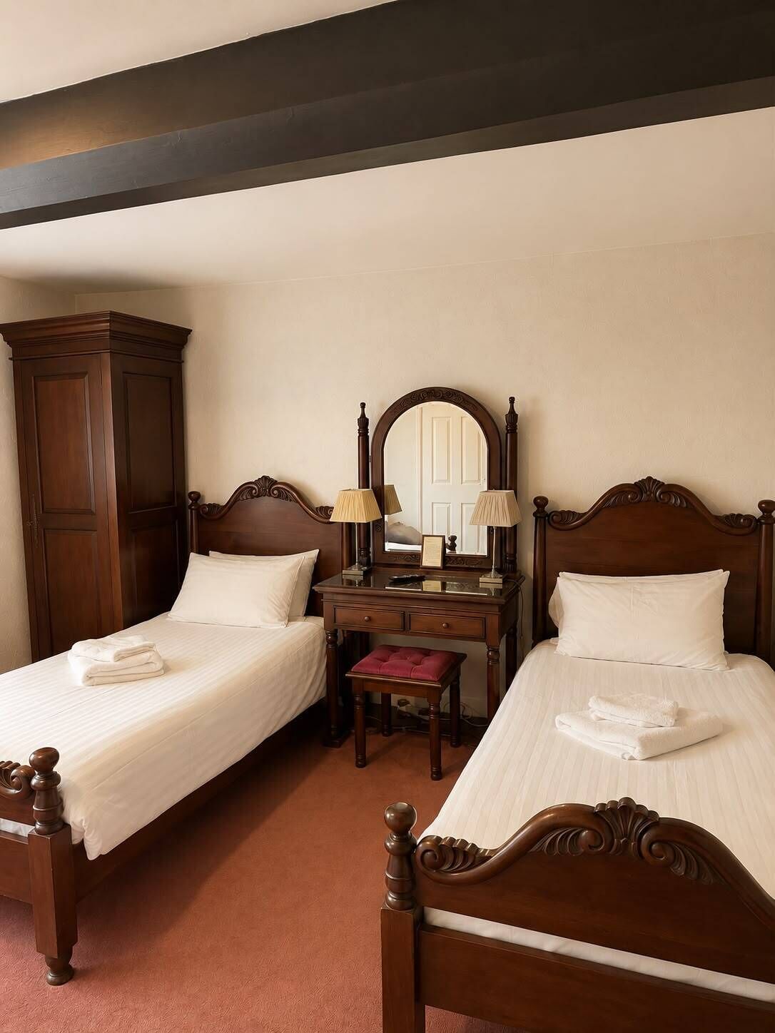 Une chambre d’hôtel avec deux lits, un bureau, un miroir et une armoire.