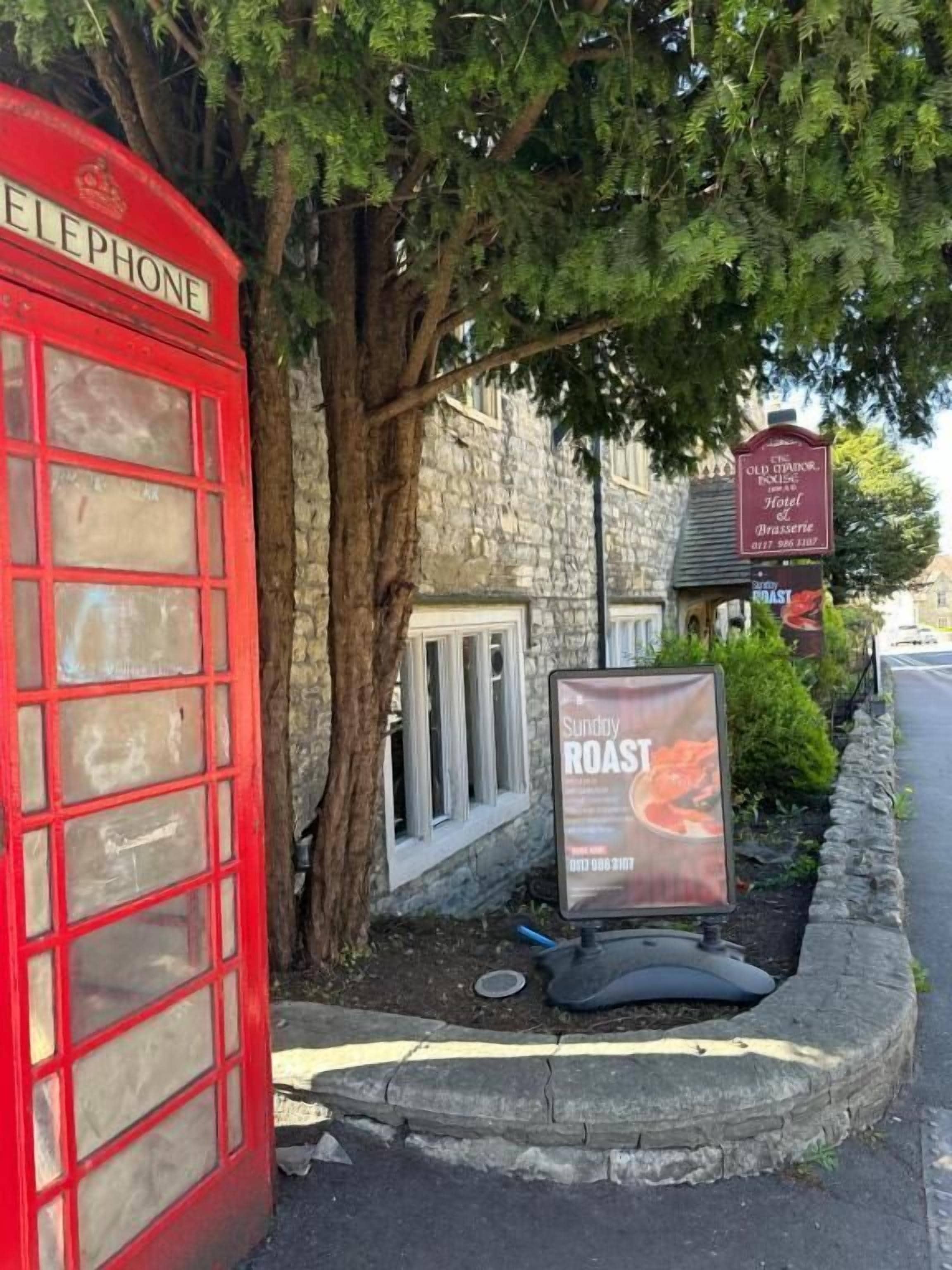 A red telephone booth, a stone building, and a sign advertising Sunflower Roasts.