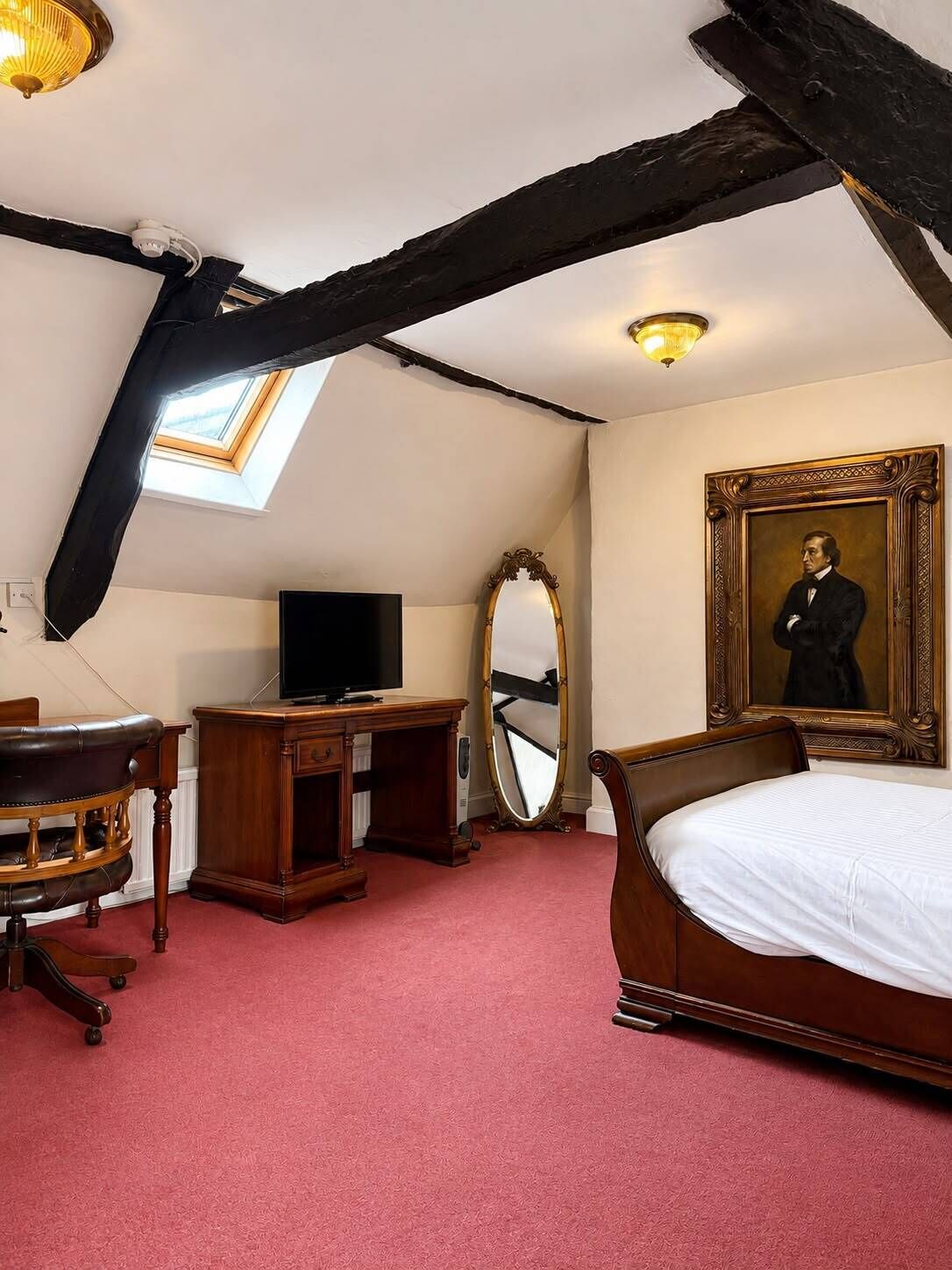 Une chambre à coucher avec un lit, un bureau, une télévision, un miroir et un tableau.