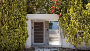 Ein Haus mit geschlossenem Eingangstor, einer kleinen Veranda und einem Blumentopf.