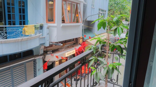 Um edifício de vários andares com varandas, um café chamado 'HAZE CAFE' e vista para a rua através das janelas.