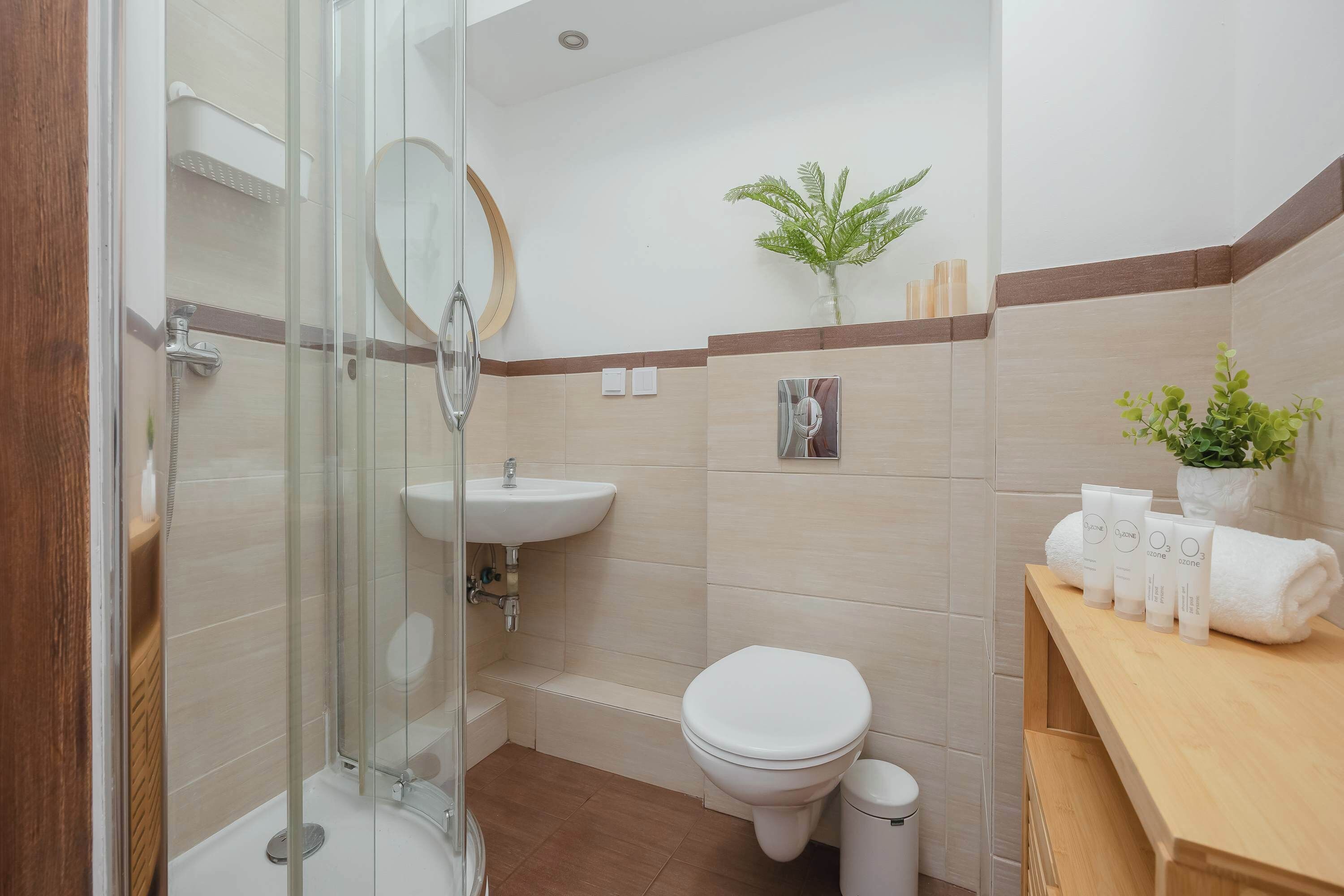 Un bagno con cabina doccia in vetro, lavandino, WC e mobile lavabo con articoli da toilette.