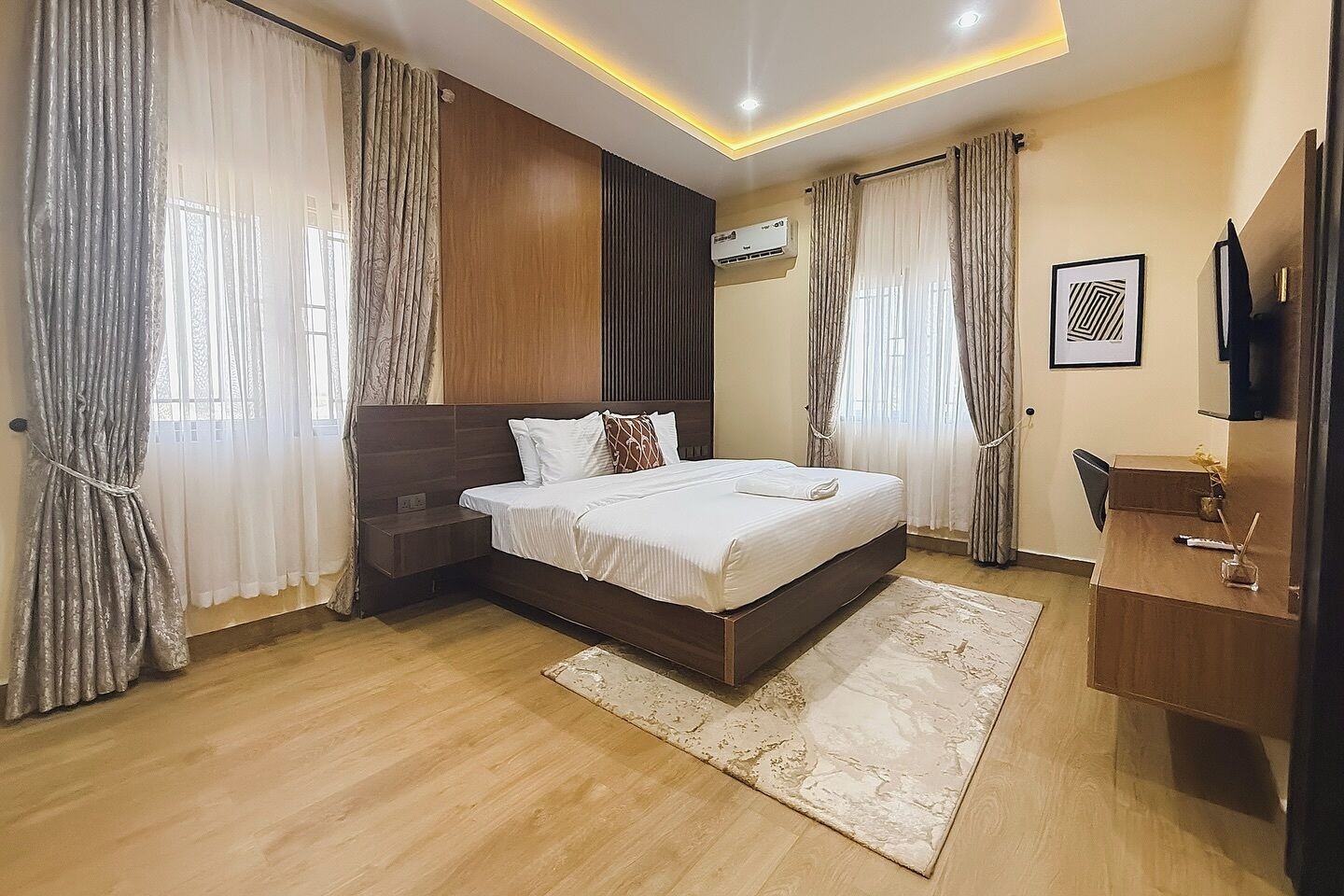 A modern hotel room with a large bed, a desk, and a TV.