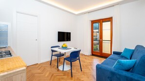 A compact living space with a kitchenette, a dining area, a sofa, and a TV. - Nicea Apartment - Sorrento center (Sorrento)