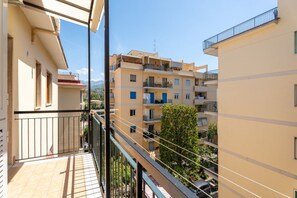 Ein Balkon mit Blick auf umliegende Gebäude und einen Baum.