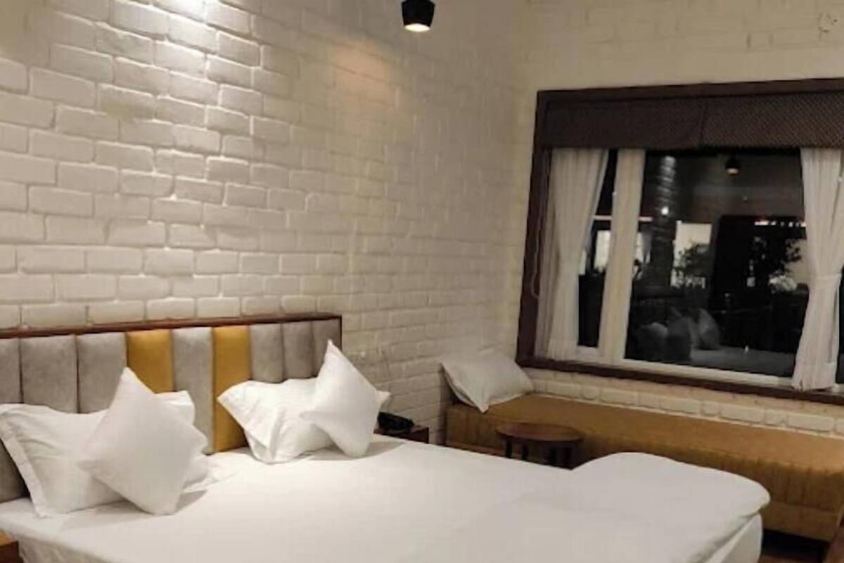 A neatly made bed with white bedding, a wooden headboard, and a window with curtains.