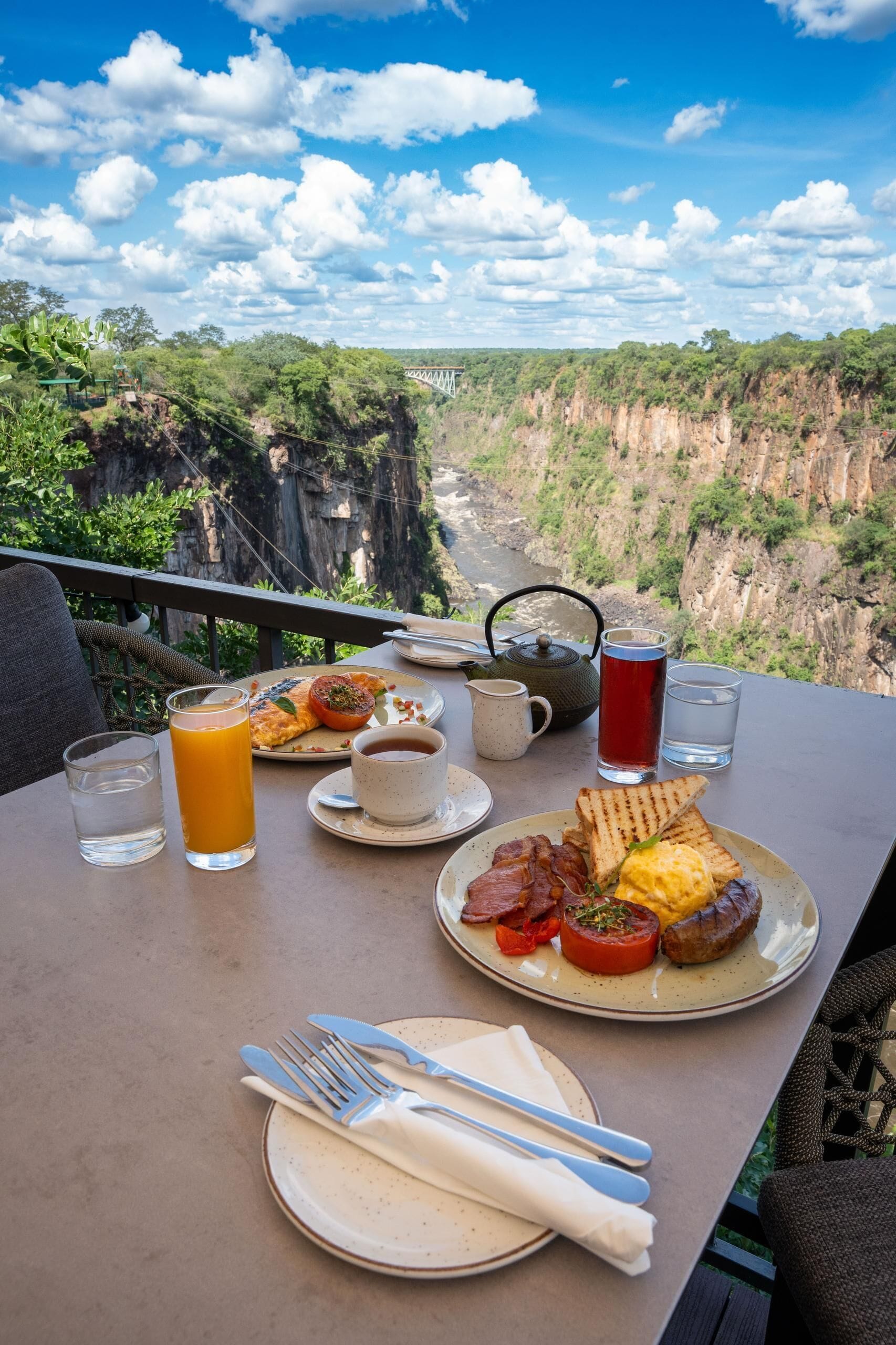 A table with breakfast, a teapot, and a view of a canyon.