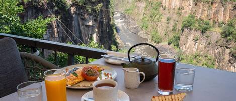 A table with breakfast, a teapot, and a view of a canyon.