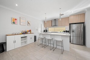 Una cucina moderna con mobili bianchi, elettrodomestici in acciaio inossidabile e un'area bar con sgabelli.