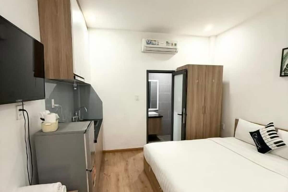 Ein Hotelzimmer mit Bett, Schreibtisch, Fernseher, Kleiderschrank und Klimaanlage.