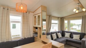 A cozy living room with a sofa, a wooden table, and a cabinet. - 21 Dunlin Dell (Bridlington)