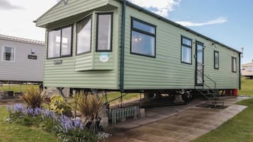 Una casa móvil verde con rampa, ventanas y un letrero que dice 'Horizon'.