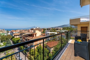 Ein Balkon mit Blick auf eine Küstenstadt, darunter Häuser und ein Berg in der Ferne.