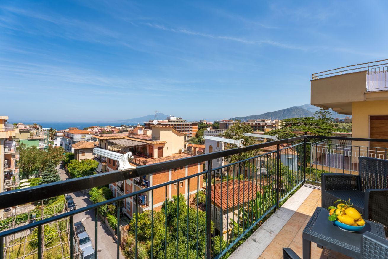 A balcony with a view of a residential area, a mountain, and a clear sky.