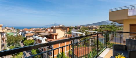 A balcony with a view of a residential area, a mountain, and a clear sky.