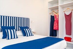 A bed with a striped headboard, pillows, and a blue bedspread. - Nerea Apartment | Sea View Balcony (Sorrento)