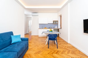 Ein kompakter Wohnbereich mit Küchenzeile, Essplatz und Sofa.