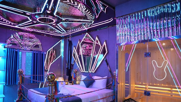 A room with a bed, a wooden sauna, and neon light decorations. - Haven Hotel (Ho Chi Minh City)