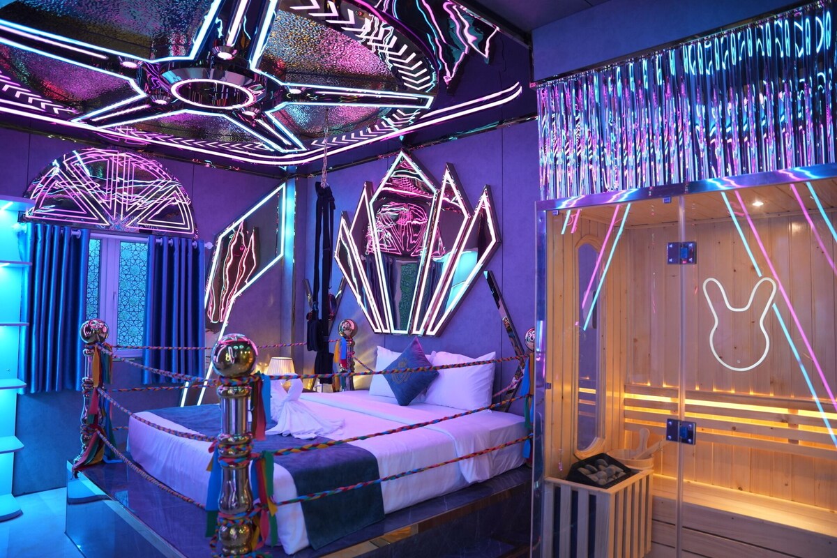 A room with a bed, a wooden sauna, and neon light decorations.