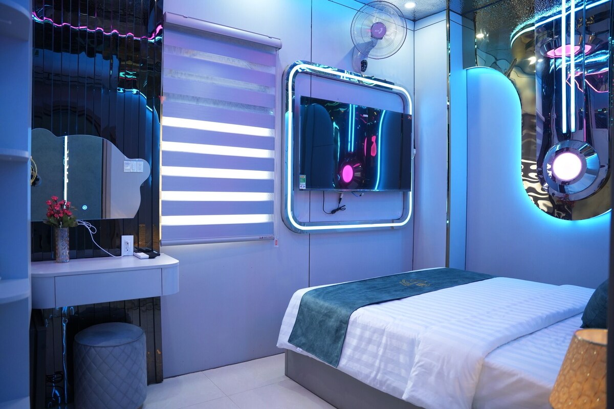 A modern bedroom with a bed, bedside table, and a window with blinds.
